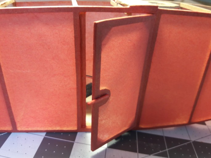 There are two opposing small 2mm magnets that hold the door shut (located under the handle) that are covered by the tissue. It's a very light and effective way to accomplish this.